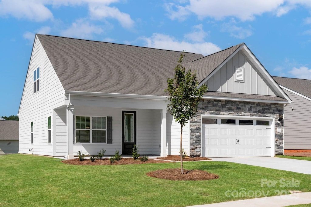 view of front of home featuring a front lawn, driveway, board and batten siding, roof with shingles, and a garage