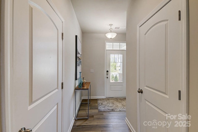 doorway with baseboards and dark wood-type flooring