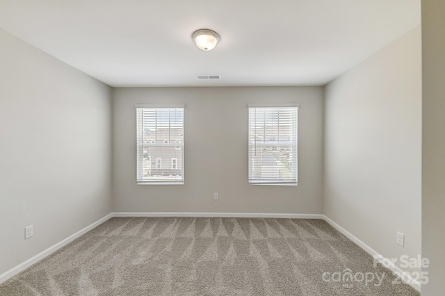 carpeted spare room with visible vents and baseboards