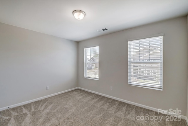 empty room with visible vents, light carpet, and baseboards