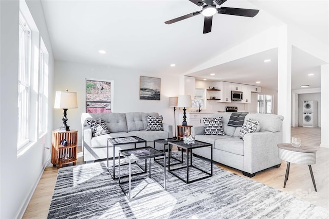 living area with washer / dryer, lofted ceiling, light wood-type flooring, and ceiling fan