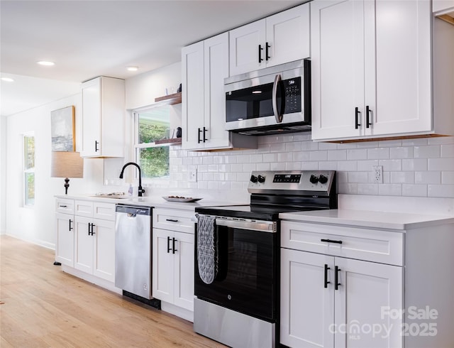 kitchen featuring light countertops, backsplash, open shelves, and stainless steel appliances