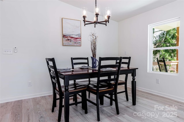 dining room with a chandelier, light wood finished floors, and baseboards