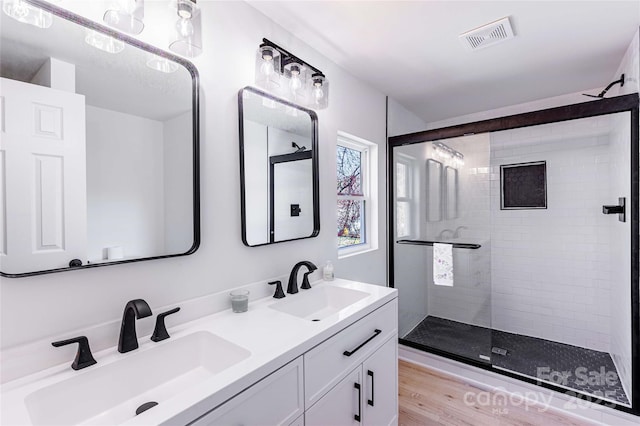 bathroom with a sink, visible vents, double vanity, and a shower stall