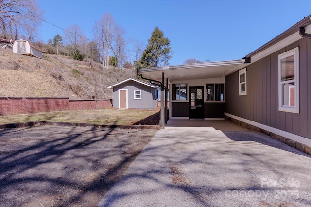 view of yard with an outbuilding, driveway, fence, a storage shed, and an attached carport