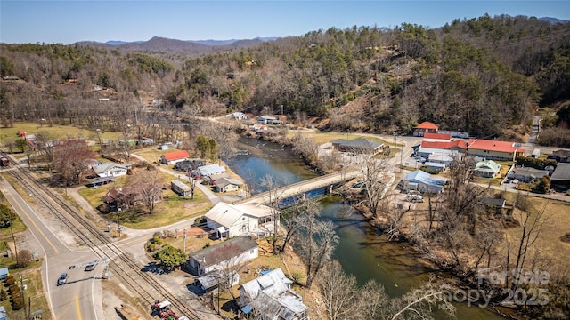 drone / aerial view with a water and mountain view and a wooded view