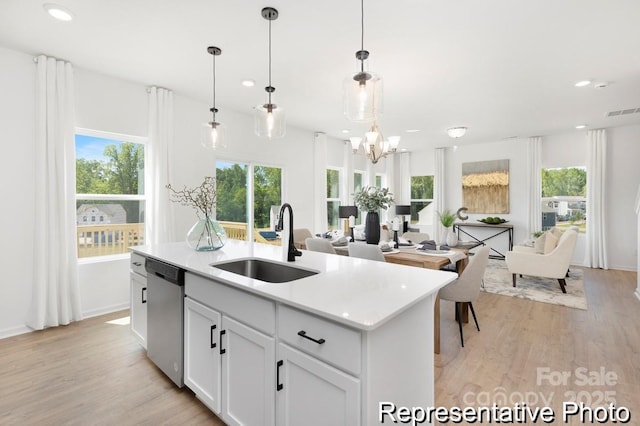 kitchen featuring light wood finished floors, open floor plan, dishwasher, an island with sink, and a sink