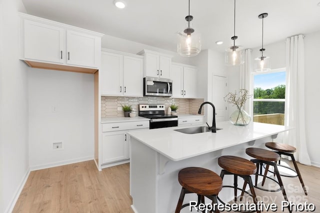 kitchen with a sink, tasteful backsplash, appliances with stainless steel finishes, and white cabinets