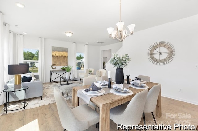 dining room with an inviting chandelier, baseboards, visible vents, and light wood finished floors