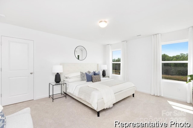 bedroom with light colored carpet, baseboards, and multiple windows