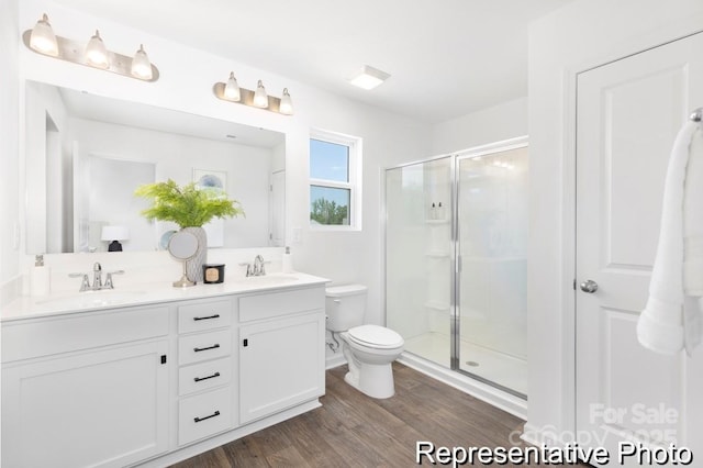 bathroom featuring a sink, wood finished floors, toilet, and a stall shower