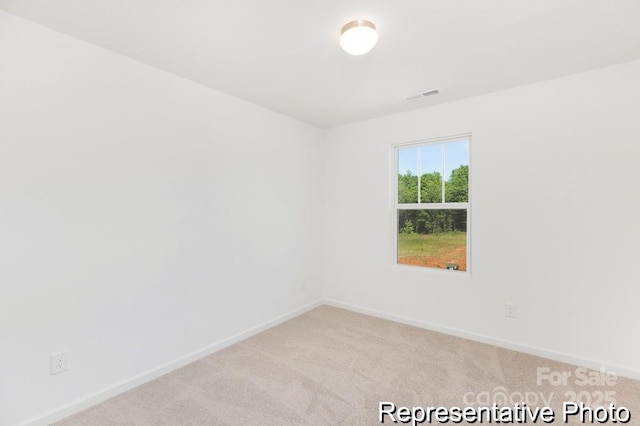 spare room featuring visible vents, light colored carpet, and baseboards