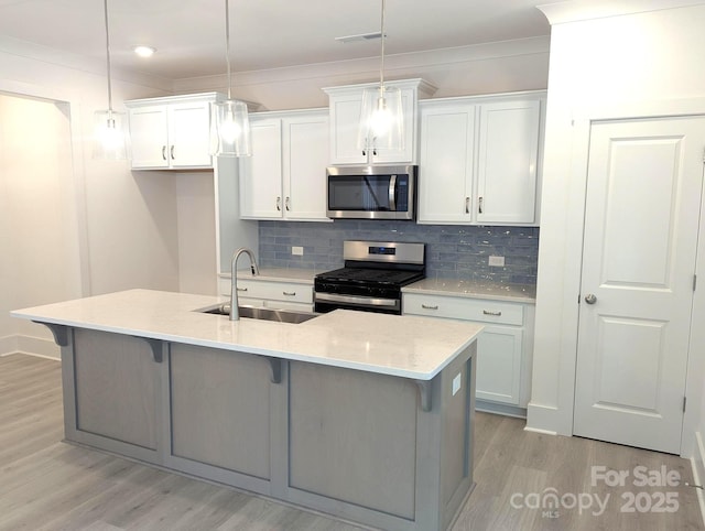 kitchen featuring stainless steel appliances, a kitchen bar, a sink, and light wood-style floors