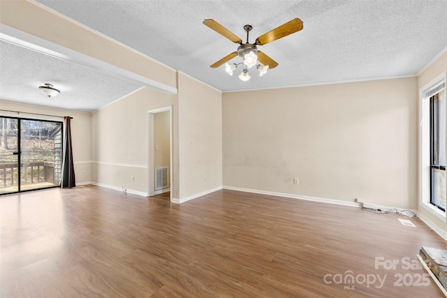 empty room with visible vents, crown molding, ceiling fan, and wood finished floors