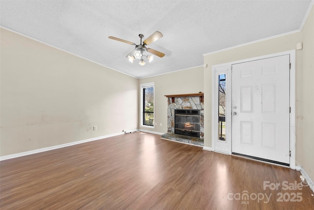 unfurnished living room with a textured ceiling, wood finished floors, a fireplace, baseboards, and ceiling fan