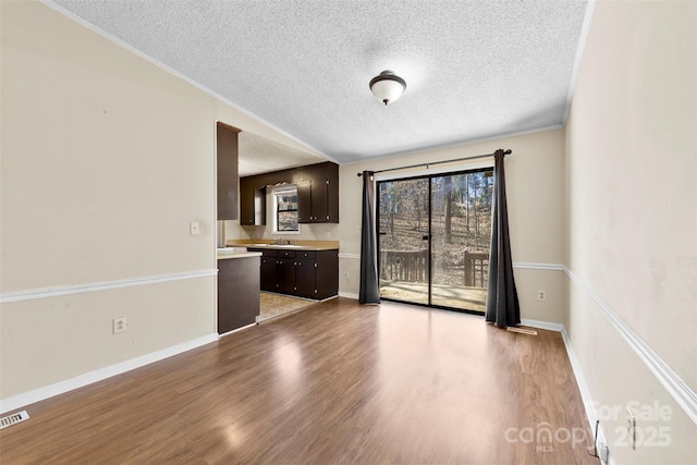 unfurnished living room with a textured ceiling, wood finished floors, baseboards, and a sink