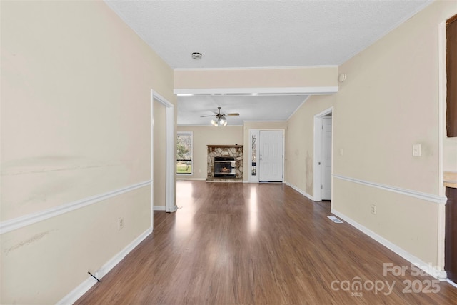 hall with visible vents, a textured ceiling, baseboards, and wood finished floors