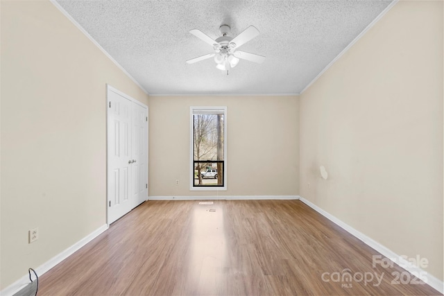 unfurnished room with wood finished floors, baseboards, ceiling fan, a textured ceiling, and crown molding