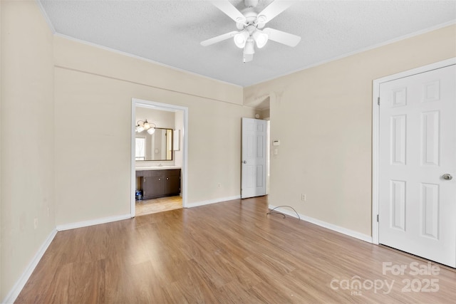 unfurnished bedroom featuring baseboards, a textured ceiling, light wood-style floors, and ornamental molding