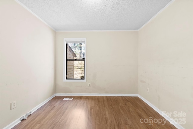 spare room featuring ornamental molding, a textured ceiling, baseboards, and wood finished floors