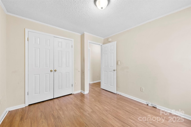 unfurnished bedroom featuring a closet, a textured ceiling, light wood-style flooring, and ornamental molding