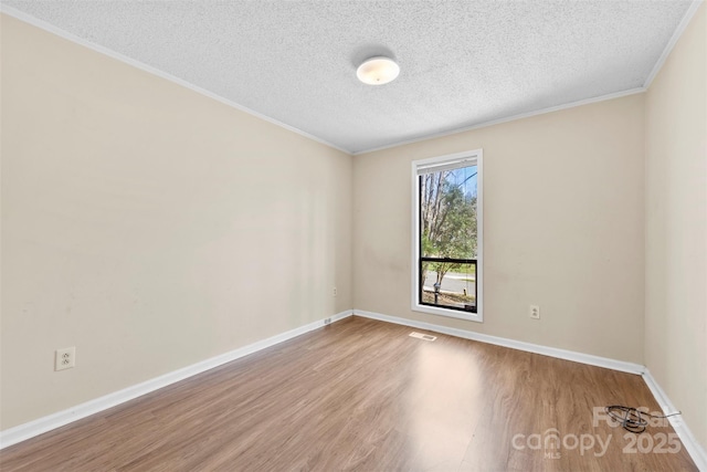 empty room featuring baseboards, a textured ceiling, wood finished floors, and ornamental molding