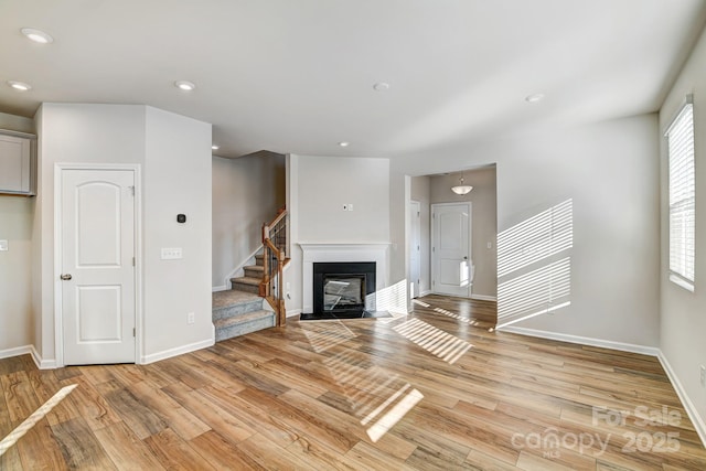 unfurnished living room with recessed lighting, baseboards, stairs, and light wood finished floors