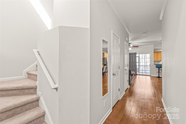 hall featuring hardwood / wood-style floors, crown molding, stairs, and baseboards