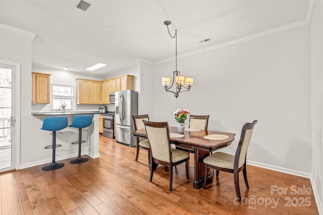 dining room with visible vents, an inviting chandelier, light wood-style flooring, and crown molding