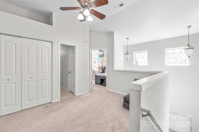 hallway featuring an upstairs landing, visible vents, baseboards, and carpet