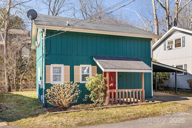 view of front of property with an attached carport, roof with shingles, and driveway