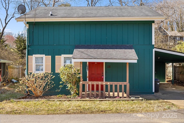 view of front of home with a carport, roof with shingles, driveway, and fence