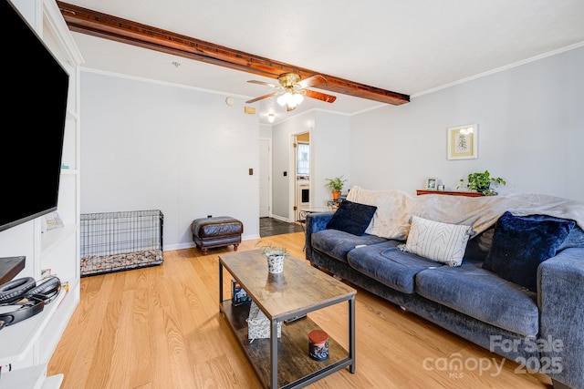 living area featuring beam ceiling, ornamental molding, light wood finished floors, baseboards, and ceiling fan