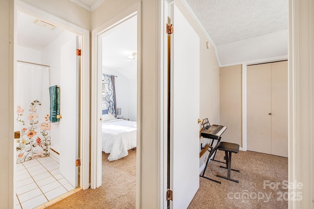 corridor with lofted ceiling, a textured ceiling, and carpet flooring