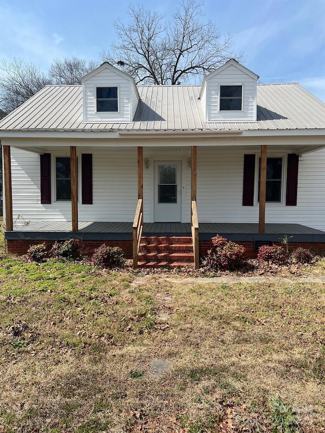 view of front facade with a standing seam roof, a porch, metal roof, and a front yard