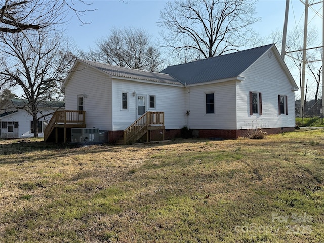 rear view of house with metal roof, a yard, and cooling unit