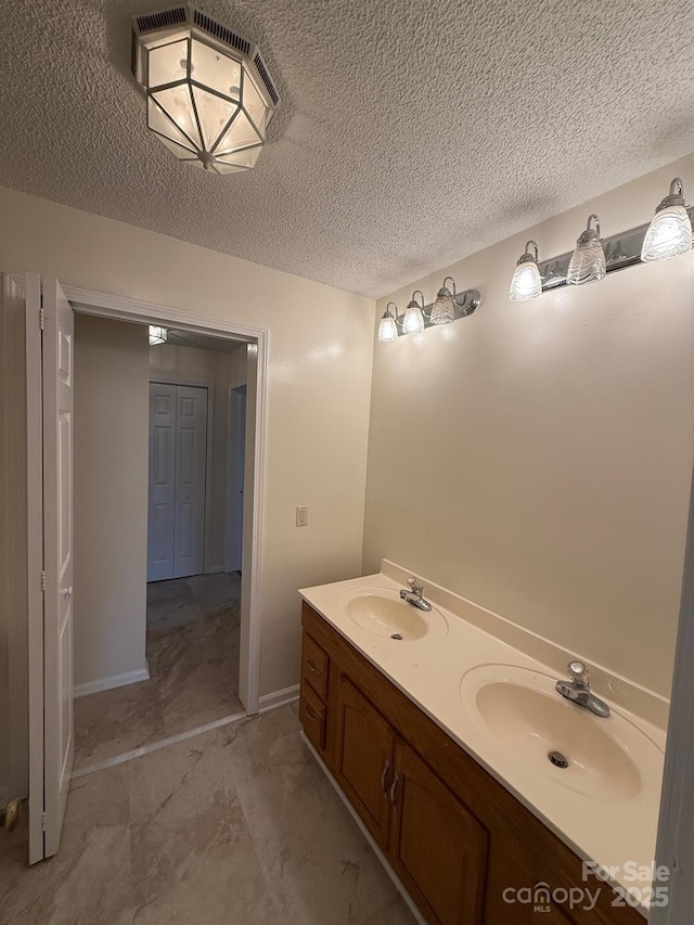 bathroom featuring double vanity, a textured ceiling, and a sink