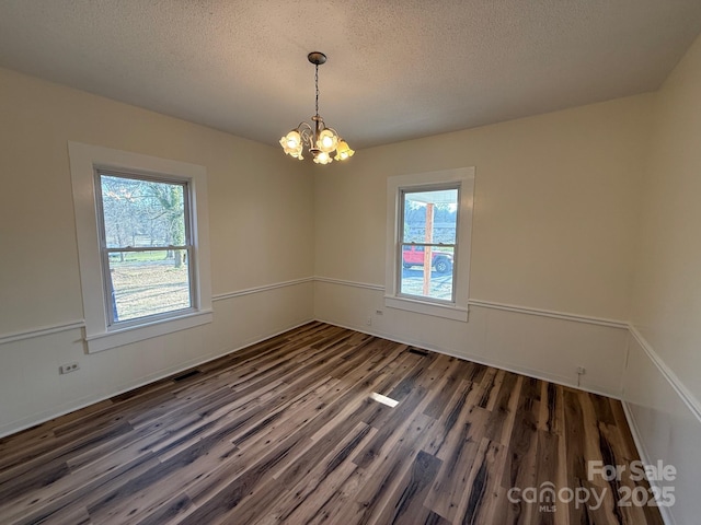 spare room featuring a wealth of natural light, wood finished floors, a chandelier, and wainscoting