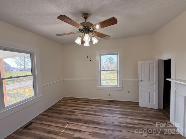 spare room featuring visible vents, plenty of natural light, and wood finished floors