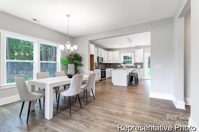 dining area with visible vents, baseboards, light wood-type flooring, recessed lighting, and an inviting chandelier