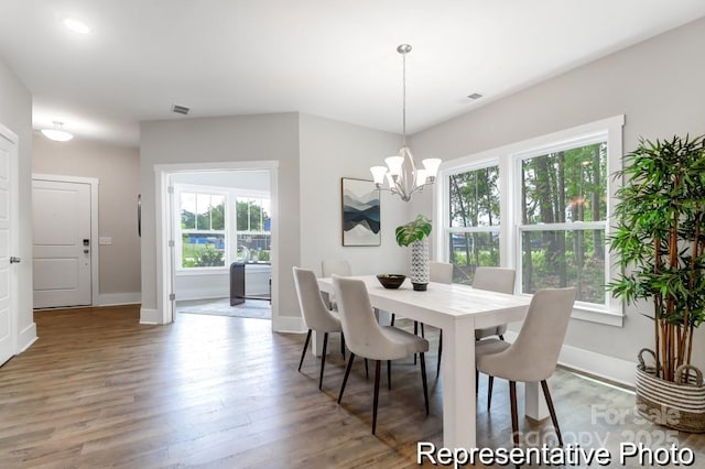 dining area with visible vents, baseboards, an inviting chandelier, and wood finished floors