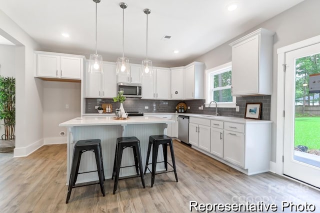 kitchen featuring backsplash, a kitchen island, appliances with stainless steel finishes, a kitchen breakfast bar, and white cabinetry