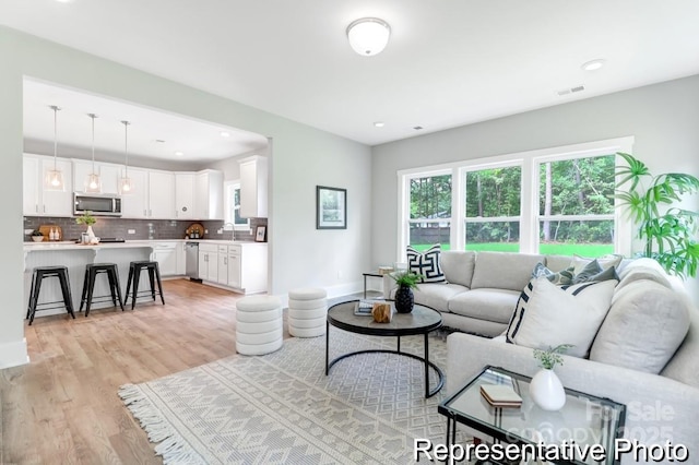 living area with recessed lighting, visible vents, plenty of natural light, and light wood-style flooring