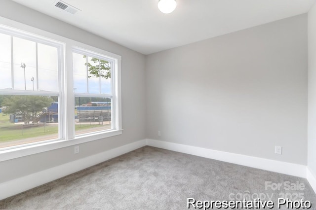 spare room with carpet flooring, baseboards, and visible vents