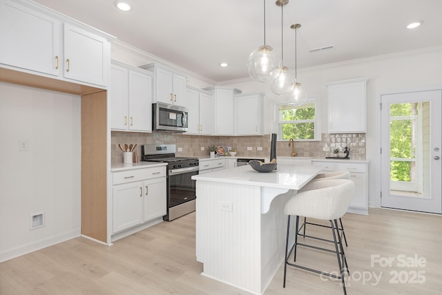 kitchen with tasteful backsplash, white cabinetry, light countertops, and appliances with stainless steel finishes