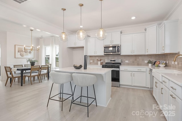 kitchen with a sink, white cabinetry, light countertops, and appliances with stainless steel finishes