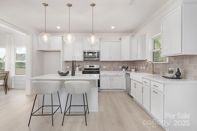 kitchen featuring light wood-style floors, appliances with stainless steel finishes, decorative backsplash, and white cabinetry