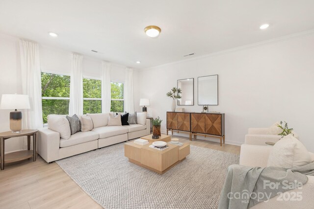 living area featuring light wood finished floors, crown molding, visible vents, and recessed lighting