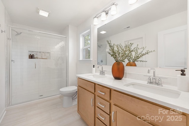 bathroom featuring toilet, visible vents, a shower stall, and a sink