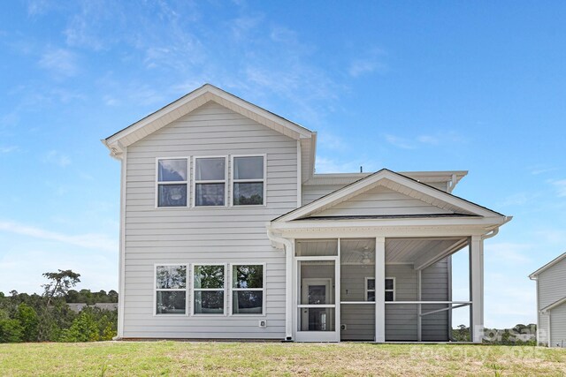 back of house featuring a lawn and a sunroom